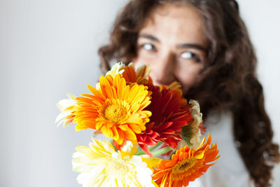 Close-up of woman with flowers against wall