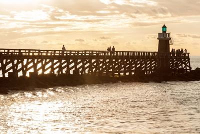 Bridge over sea against sky during sunset