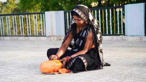 Indian woman cutting a fresh papaya. peeling the skin of ripe papaya with a knife