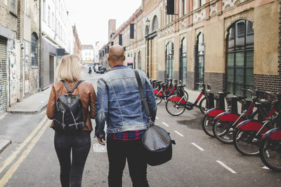 Full length rear view of multi-ethnic couple walking on city street