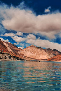 Scenic view of lake by mountains against sky