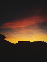 Silhouette buildings against dramatic sky during sunset