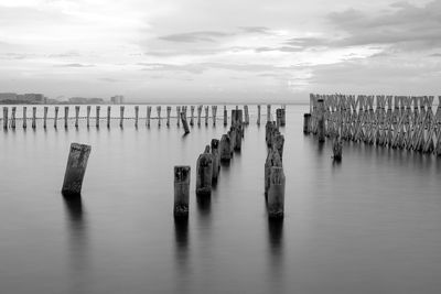 Wooden posts in sea against sky