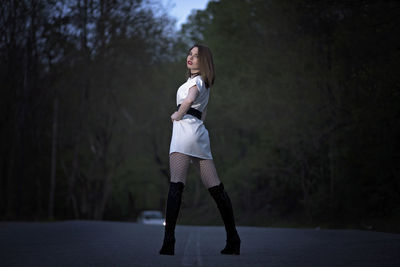 Full length of young woman looking away while standing on tree