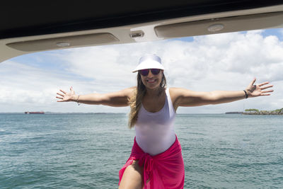 Portrait of young woman wearing sunglasses while standing at beach