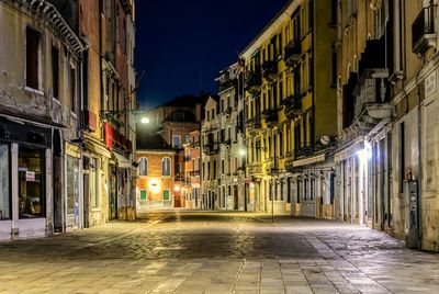 Empty street amidst buildings at night