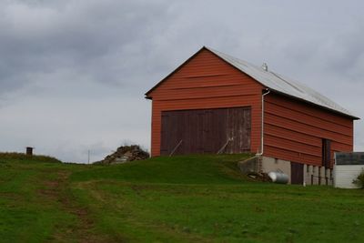 Barn on field against cloudy sky