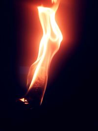 Close-up of illuminated candle against black background