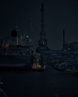 Sailboats moored at harbor against sky at night