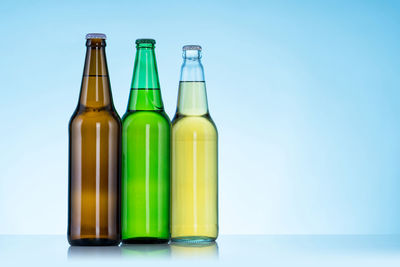 Green bottles on table against blue background