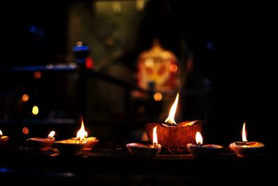 Close-up of lit candles in temple at night