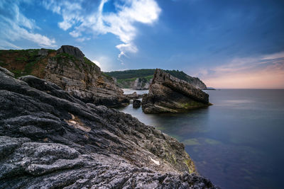 Scenic view of sea by cliff against sky