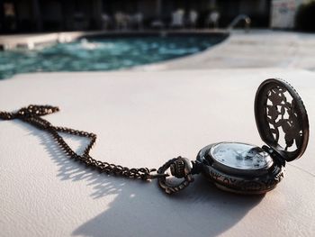 Close-up of pocket watch at poolside during sunny day