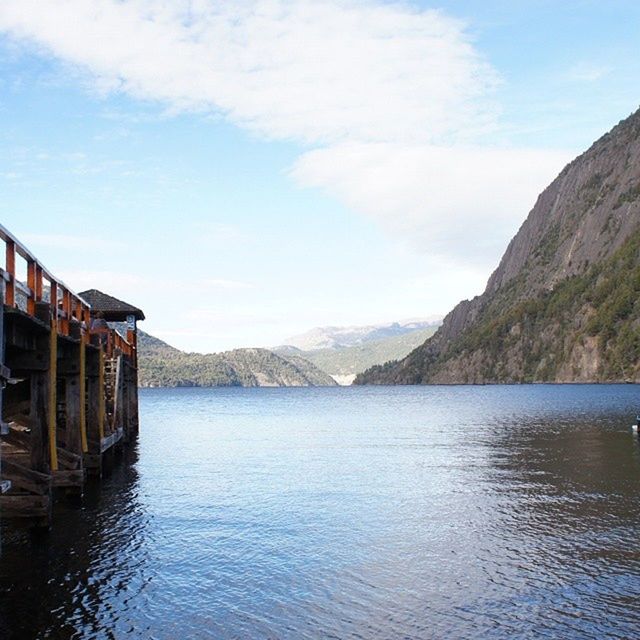 mountain, water, waterfront, sky, mountain range, lake, tranquil scene, tranquility, scenics, built structure, cloud - sky, rippled, beauty in nature, architecture, nature, cloud, building exterior, reflection, river, idyllic