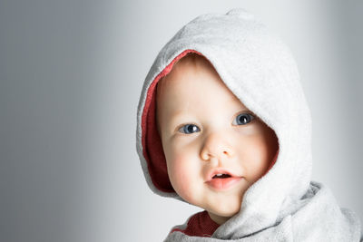 Portrait of cute baby boy wearing hooded shirt against gray background