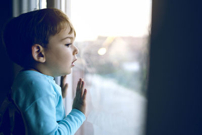 Close-up of boy looking through glass window