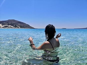 Rear view of woman in sea against clear blue sky
