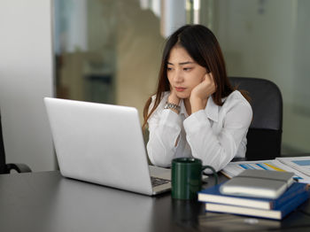 Depressed businesswoman looking at laptop in office