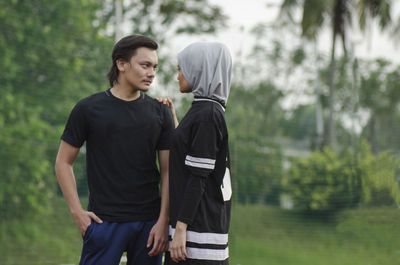 Young couple standing against trees