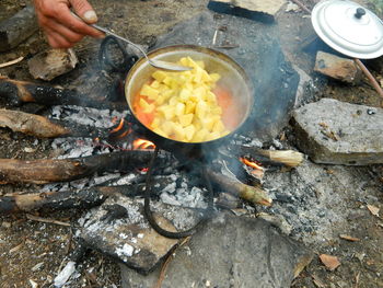 Cropped image of person cooking food on bonfire