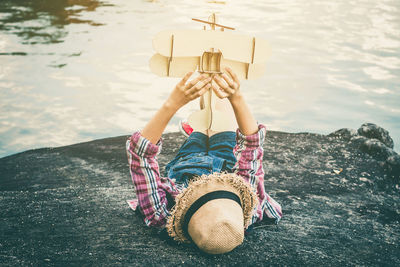 Woman with toy airplane lying down at lake