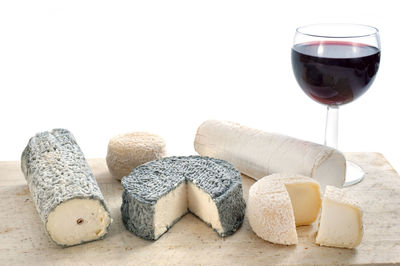 Close-up of wine with cheese on table against white background