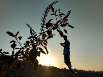 Silhouette man with tree against sky during sunset