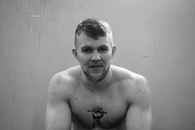 Portrait of shirtless man standing against wall