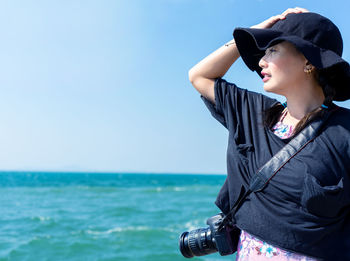 Woman photographing sea against clear sky