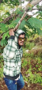 Midsection of man wearing sunglasses standing in forest