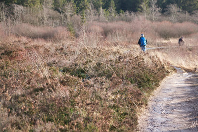 Rear view of people hiking on field