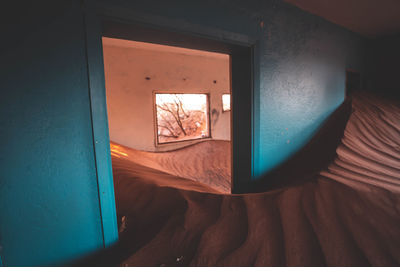 High angle view of open door of house filled with sand