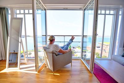 Rear view of man relaxing on chair by balcony