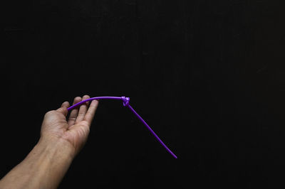 Midsection of person holding illuminated lighting equipment against black background