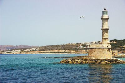 Lighthouse amidst sea against clear sky