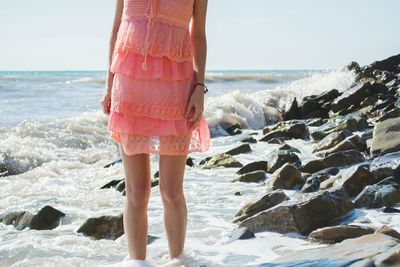 Scenic view of woman in pink dress wading through surf