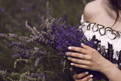 Midsection of woman standing by purple flowering plants