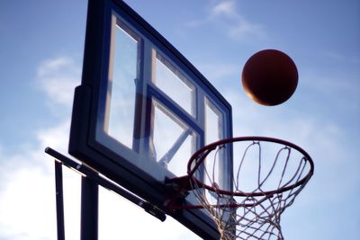 Low angle view of basketball over hoop against sky