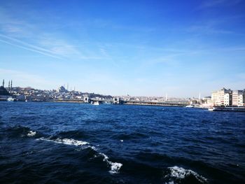 View of city at waterfront against blue sky