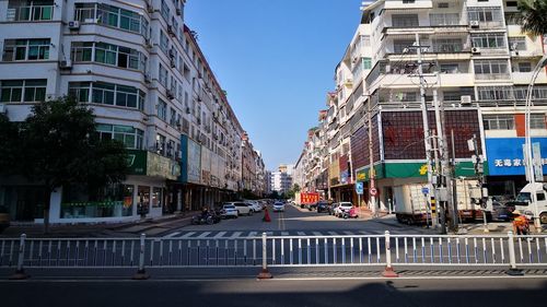 Cars on road by buildings against sky