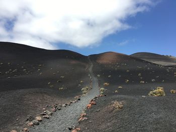 Footpath at desert against sky