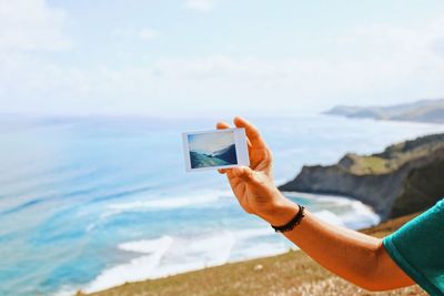 Midsection of man photographing sea against sky