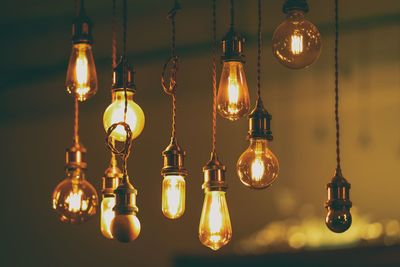 Low angle view of illuminated light bulbs hanging from ceiling