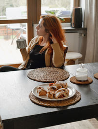 Woman drinking hot tea on the kitchen by table on sunny morning. person relaxing having coffee