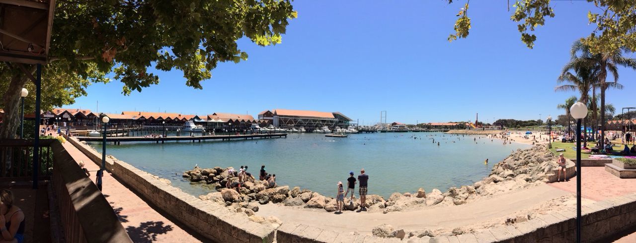 clear sky, water, blue, built structure, sea, building exterior, tree, beach, architecture, sunlight, copy space, shadow, day, shore, nature, leisure activity, panoramic, relaxation, sand