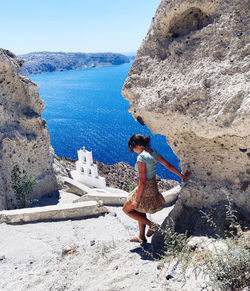 Rear view of woman standing on rock at beach