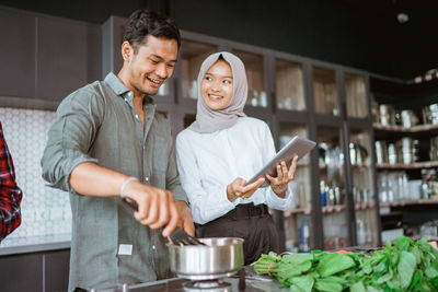 Smiling couple making food in kitchen