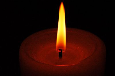 Close-up of illuminated candle in darkroom