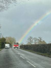 Rainbow over road against sky