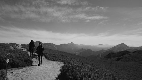 Rear view of women walking on mountain against sky